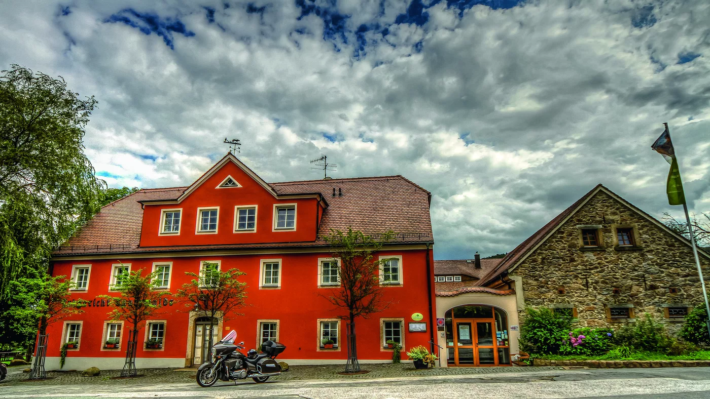 Rotes Barockgebäude mit Nebengebäude unter Wolkenhimmel Rotes Barockgebäude mit Nebengebäude unter Wolkenhimmel